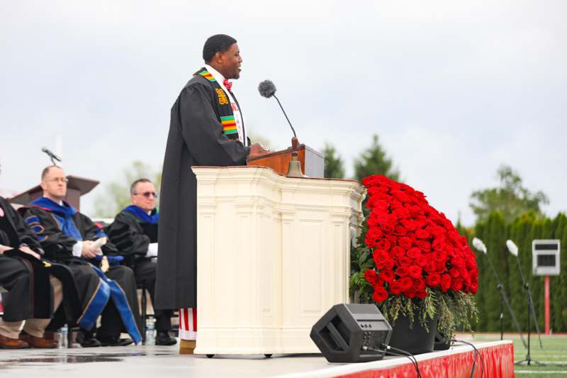a man in a robe standing at a podium with a microphone
