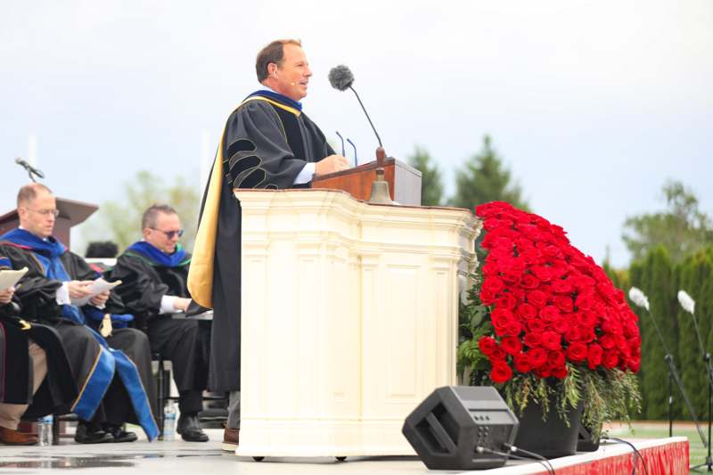 a man in a robe standing at a podium with a microphone