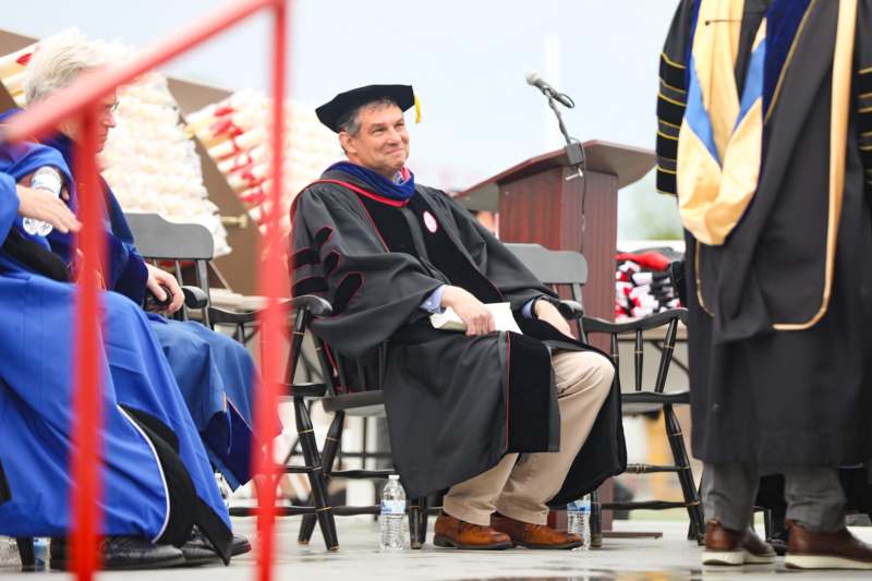 a man in a graduation gown sitting in a chair