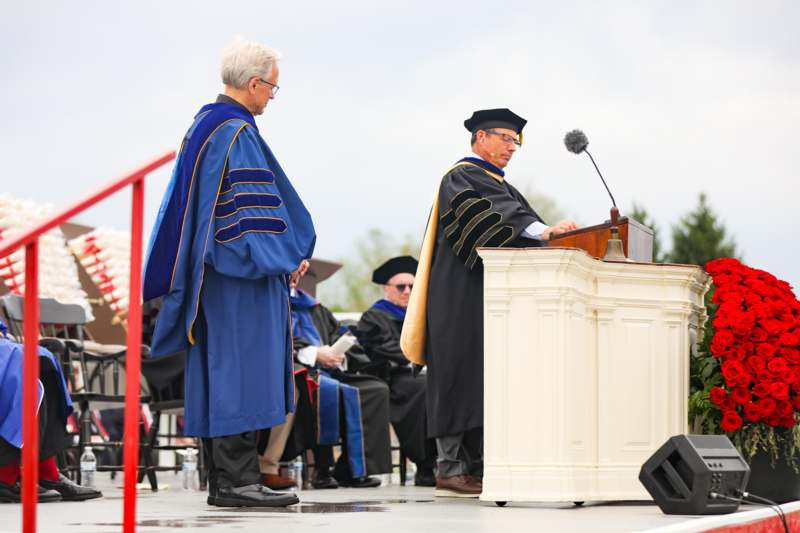 a group of men wearing graduation gowns and cap standing at a podium