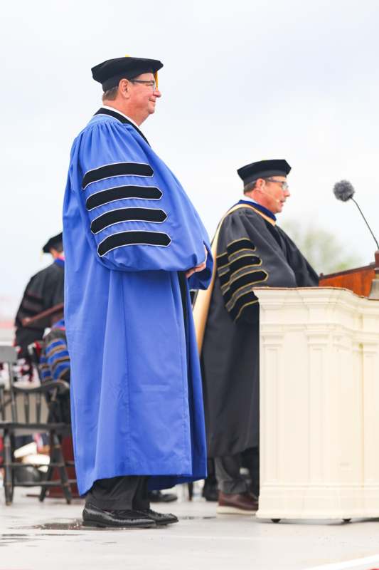 a man in a blue robe standing in front of a podium