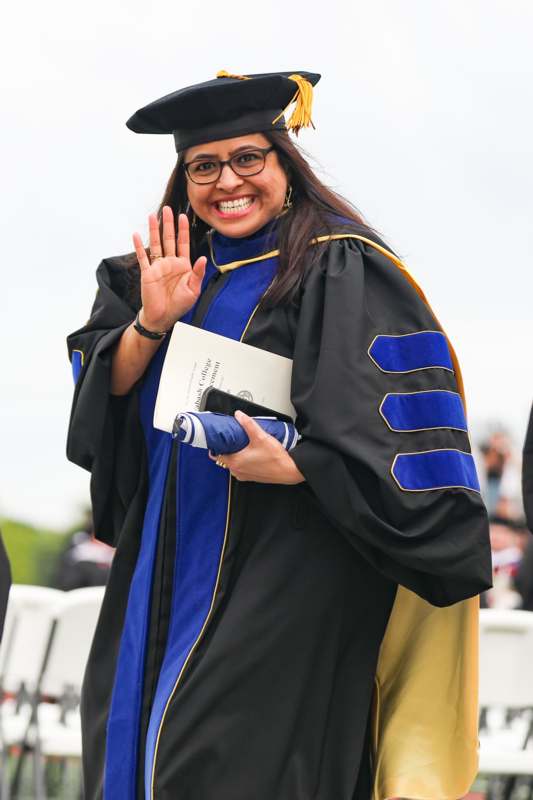a woman in a graduation gown waving