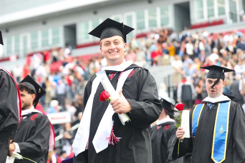a man in graduation gown and cap holding a diploma