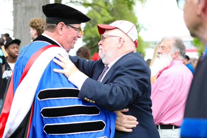a man in a cap and a robe hugging another man