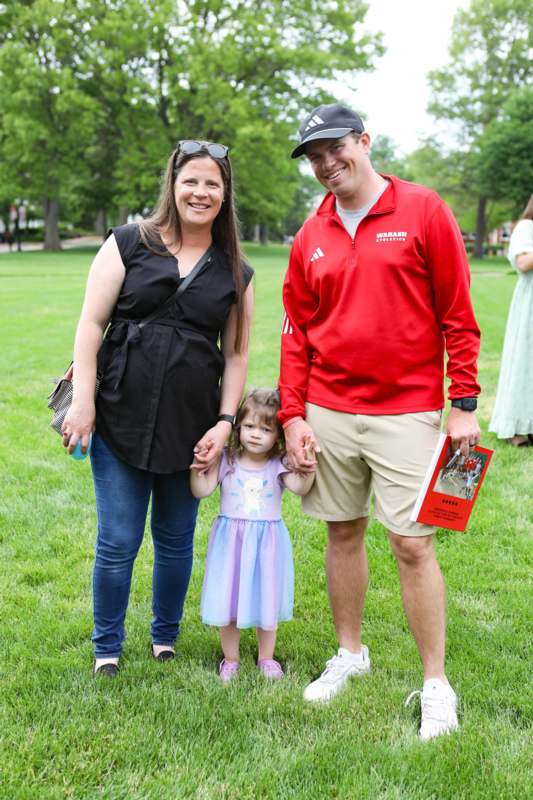 a man and woman standing in a park with a child