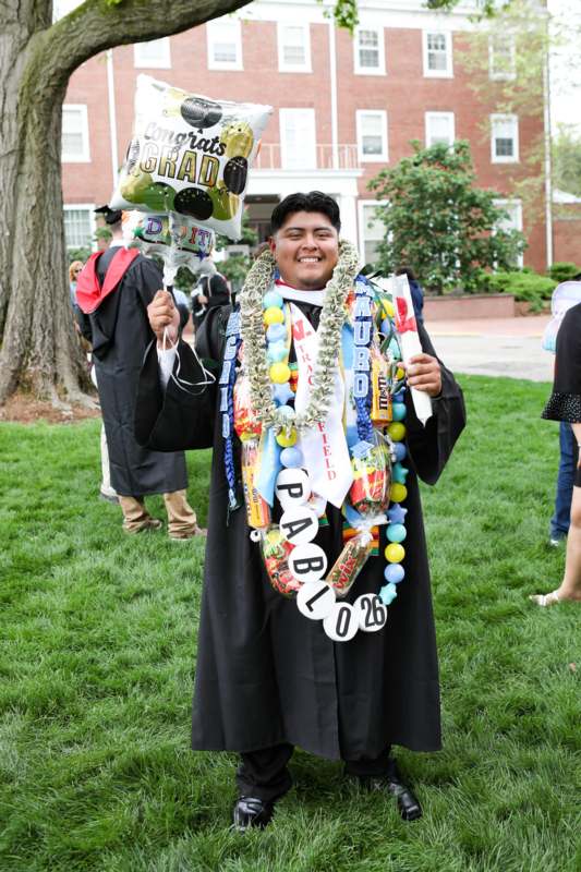 a man in a graduation gown holding balloons and a balloon