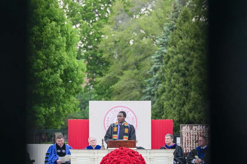 a man standing at a podium with a group of people in the background