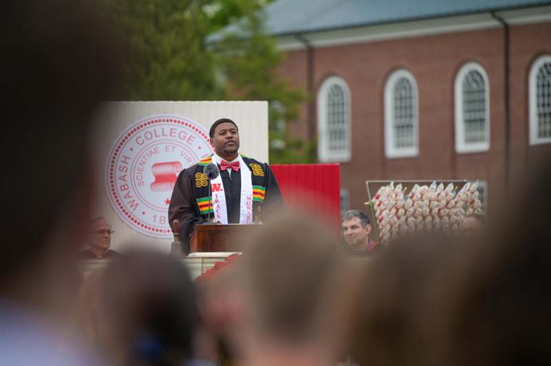 a man standing at a podium with a crowd of people behind him