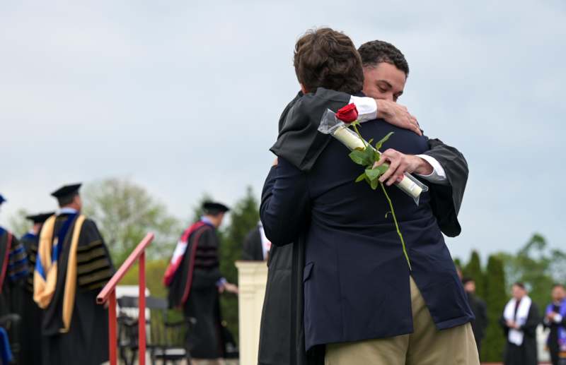 a man hugging another man with a rose