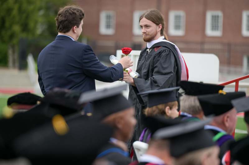 a man giving a rose to another man