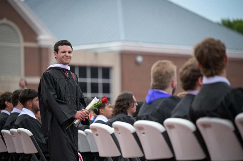 a man in a graduation gown holding flowers