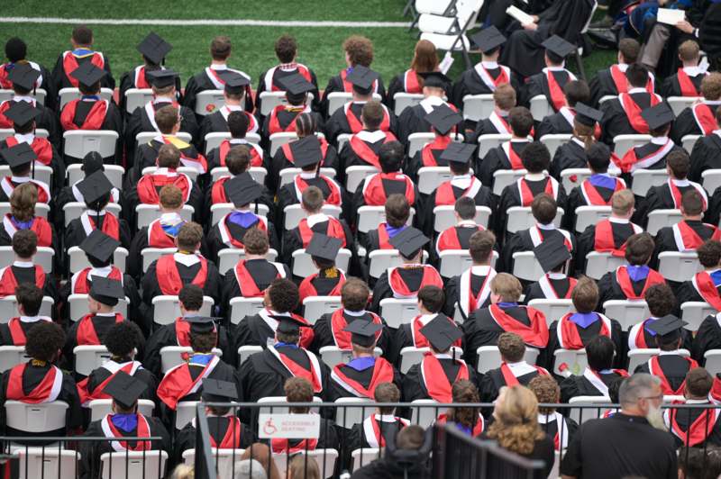 a group of people in graduation gowns and caps sitting in chairs