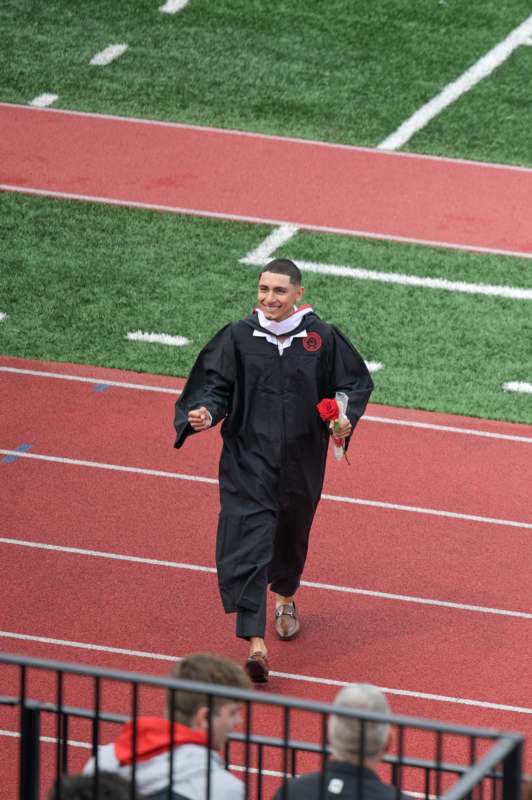 a man in a graduation gown walking on a track