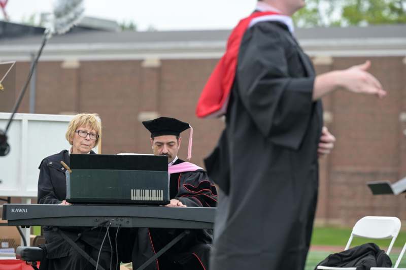 a group of people in graduation gowns playing a piano