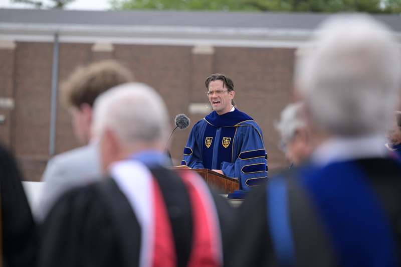 a man in a blue robe speaking into a microphone
