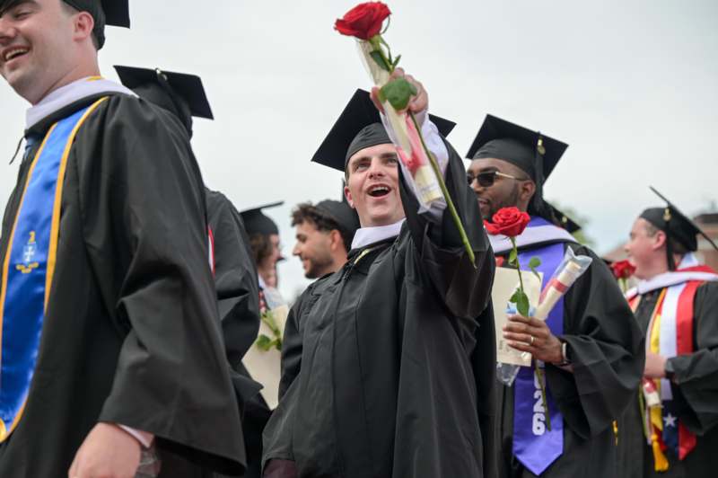 a man in graduation gown holding a rose