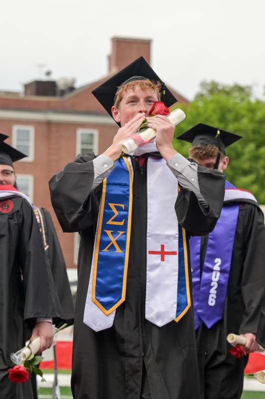 a man in a graduation gown holding a rose