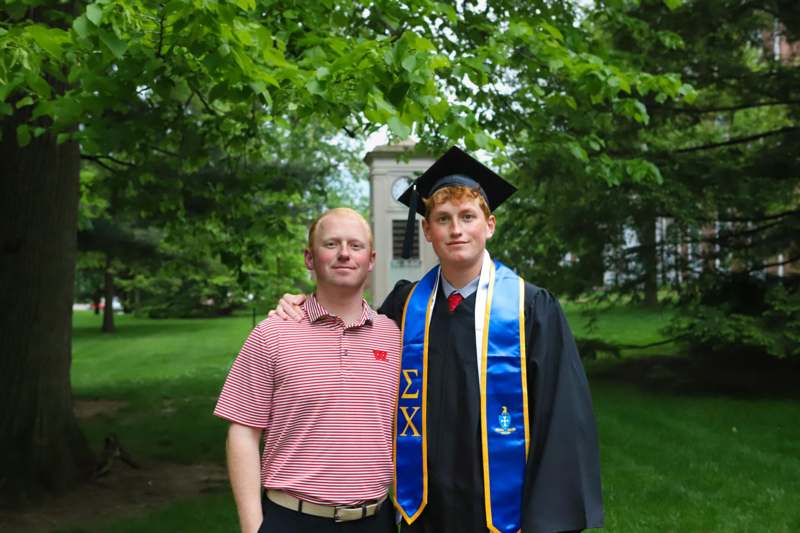 a man in a graduation gown and cap standing next to a man in a cap and gown