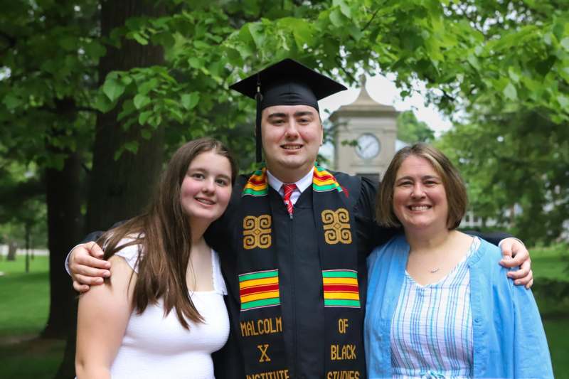 a man in a graduation cap and gown with two women