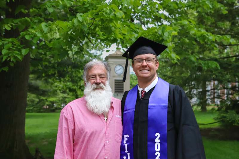a man in a graduation cap and gown standing next to a man in a cap and gown