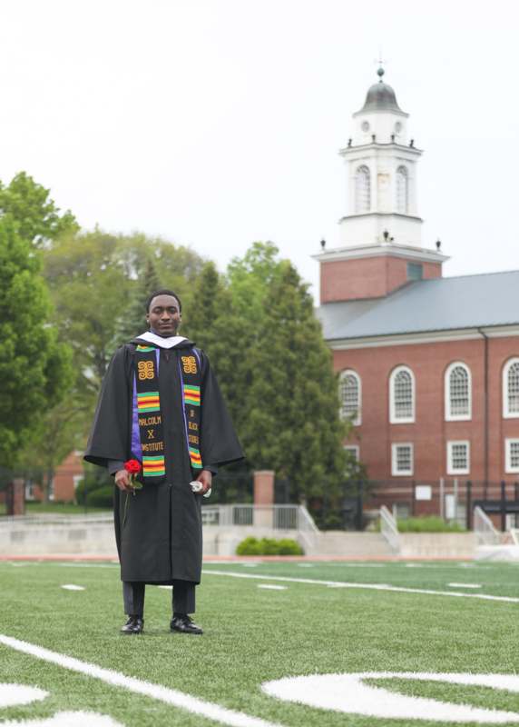 a man in a graduation gown holding a rose