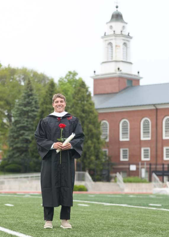 a man in a graduation gown holding a rose