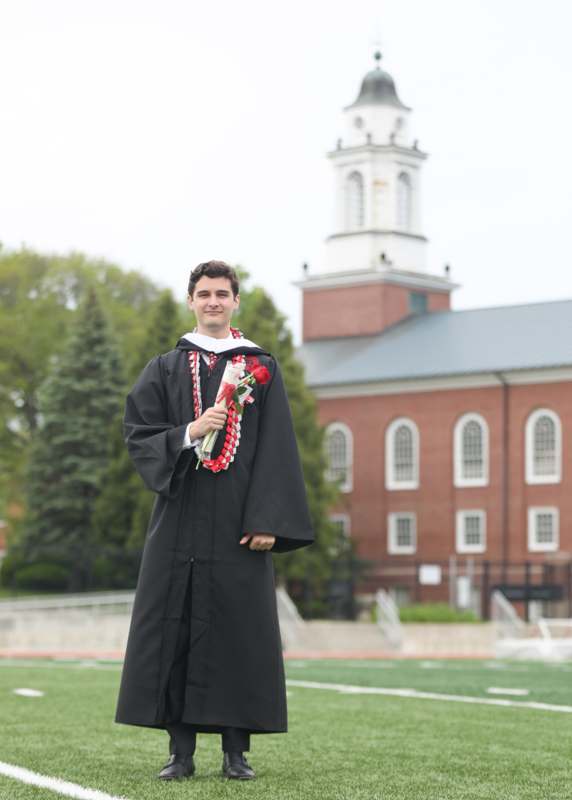 a man in a graduation gown holding a bouquet of flowers