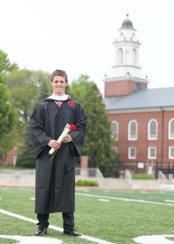a man in a graduation gown holding a rose