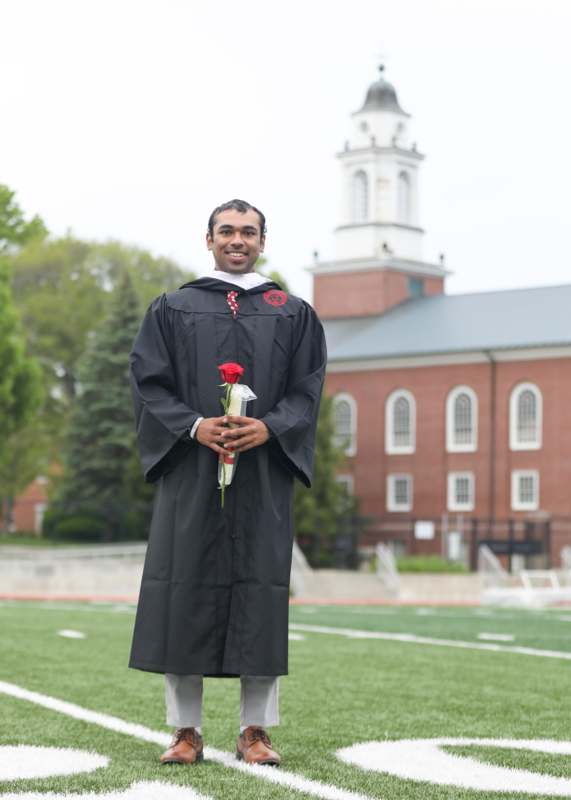a man in a graduation gown holding a rose