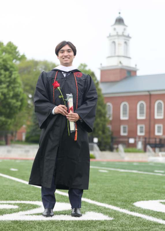 a man in a graduation gown holding a rose