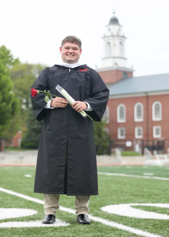 a man in a graduation gown holding a rose