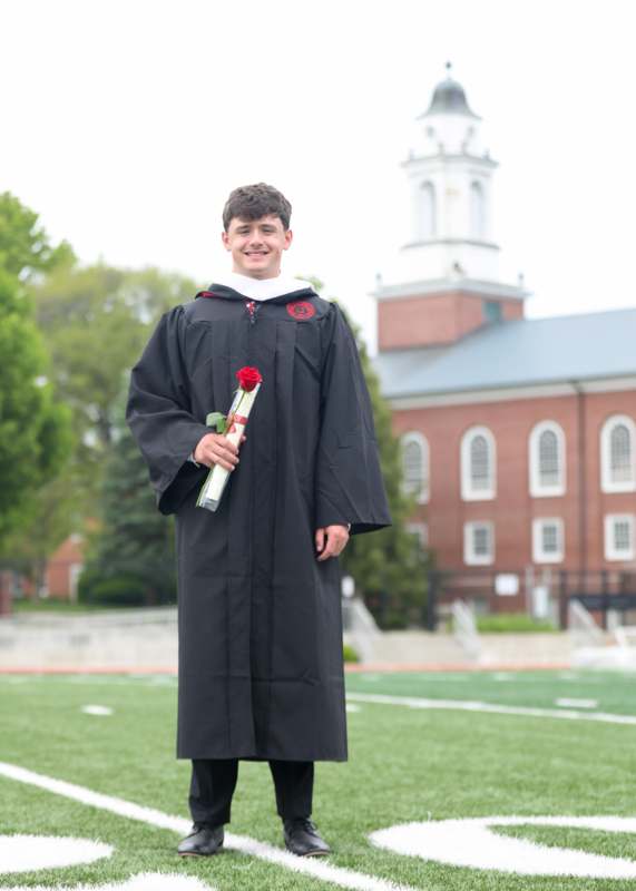 a man in a graduation gown holding a rose