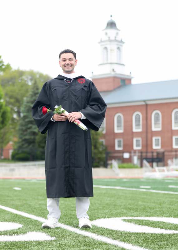 a man in a graduation gown holding a rose