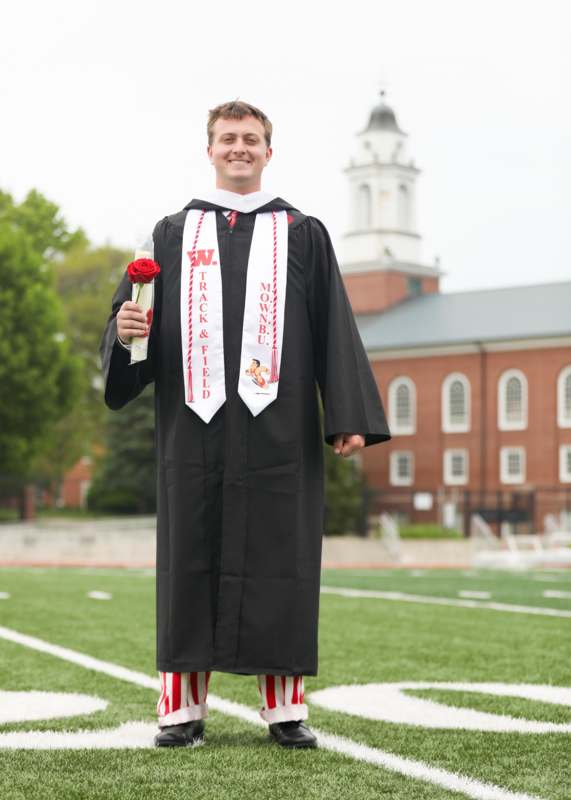 a man in a graduation gown holding a rose and a red rose