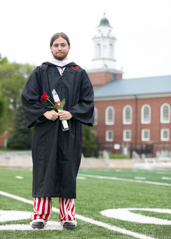a man in a graduation gown holding a rose