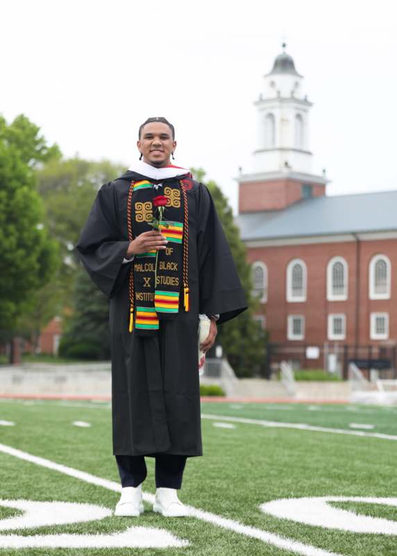 a man in a graduation gown holding a rose