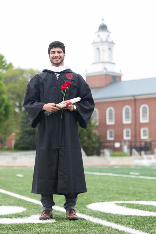 a man in a graduation gown holding a rose