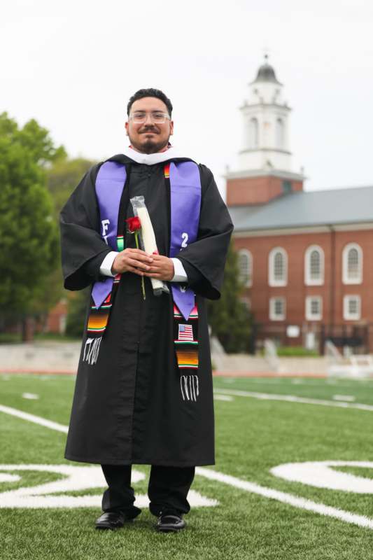 a man in a graduation gown holding a rose