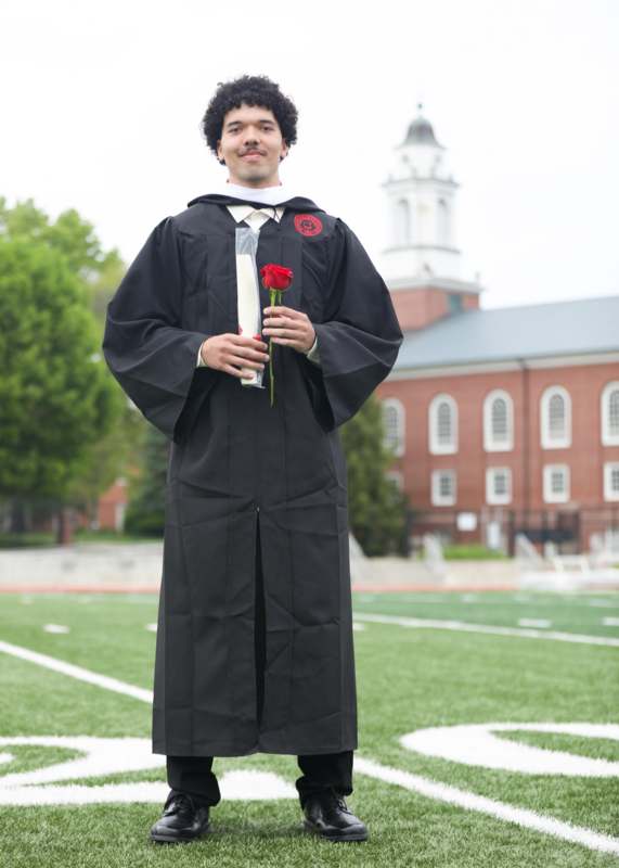 a man in a graduation gown holding a rose