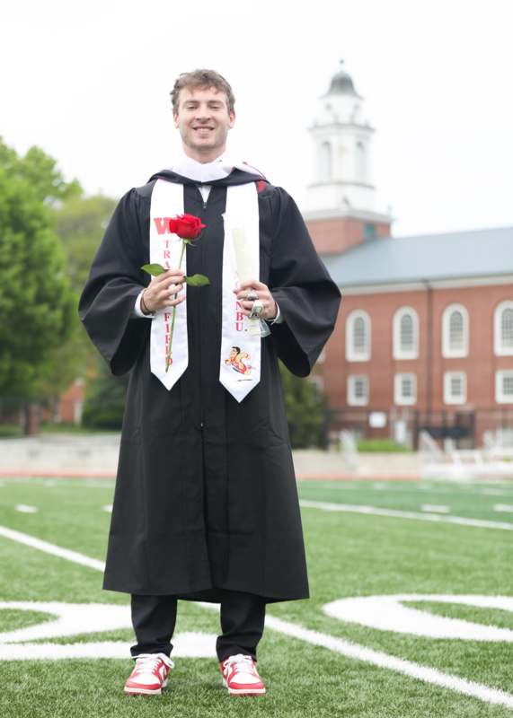 a man in a graduation gown holding a rose