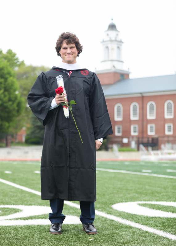 a man in a graduation gown holding a rose