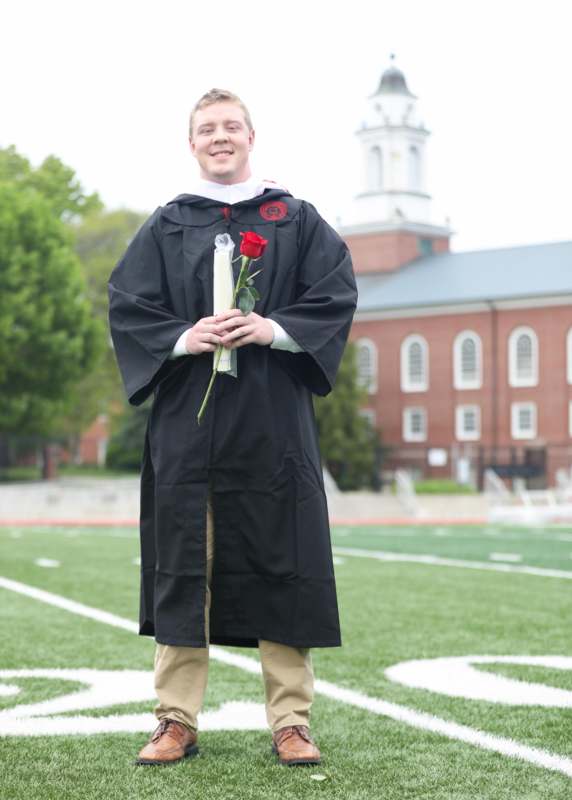 a man in a graduation gown holding a rose