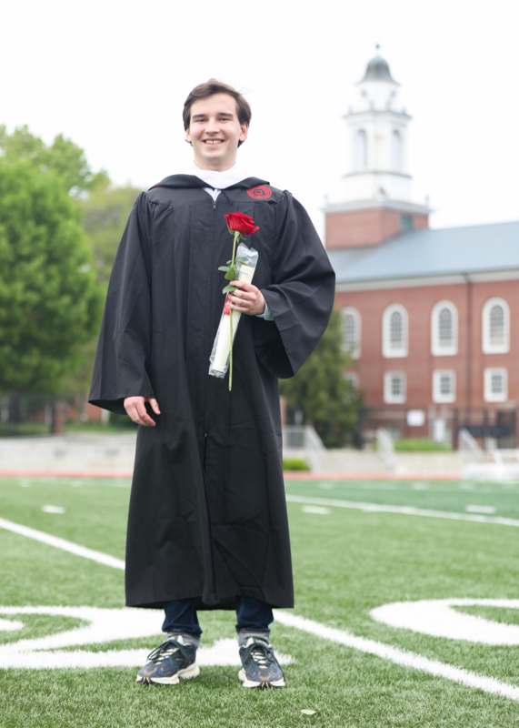 a man in a graduation gown holding a rose