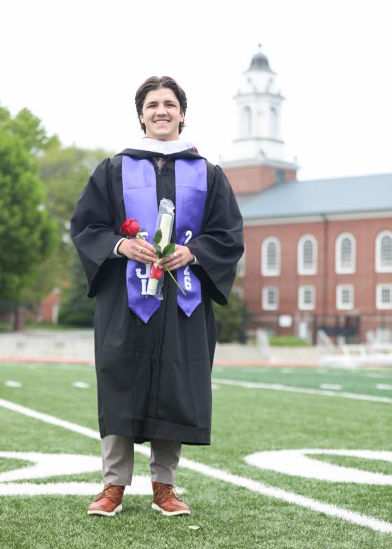 a man in a graduation gown holding a rose and a flower