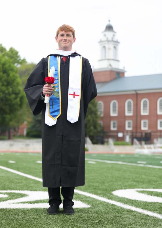 a man in a graduation gown holding a rose