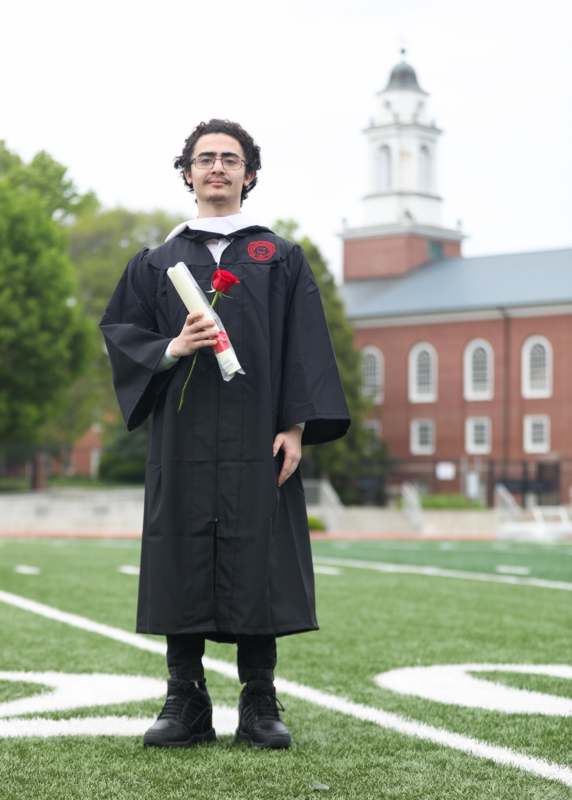 a man in a graduation gown holding a rose