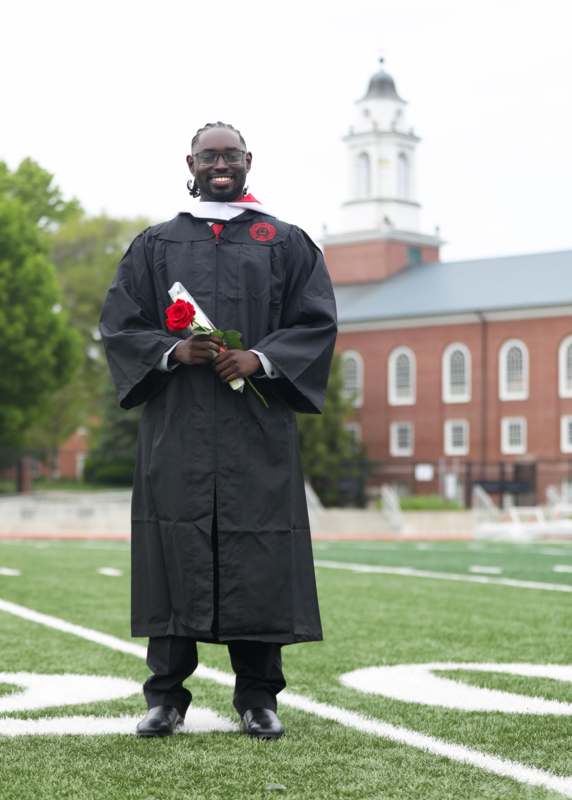 a man in a graduation gown holding a rose