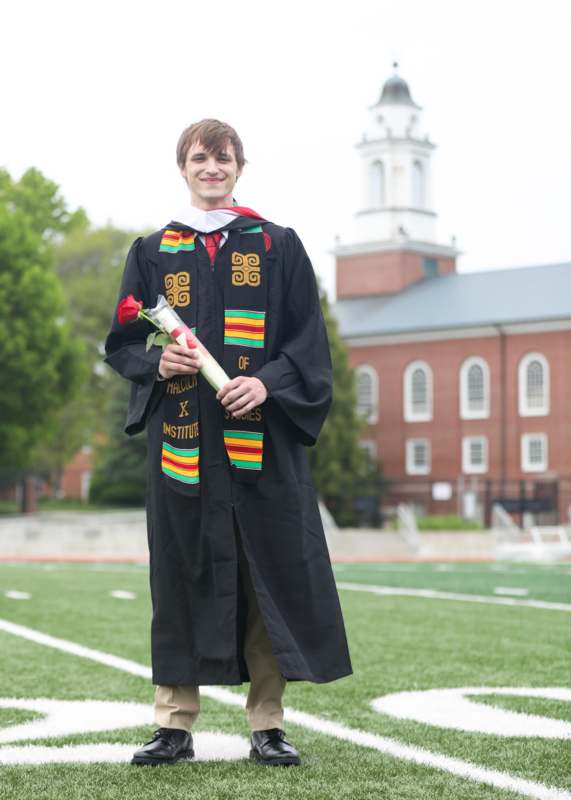 a man in a graduation gown holding a rose