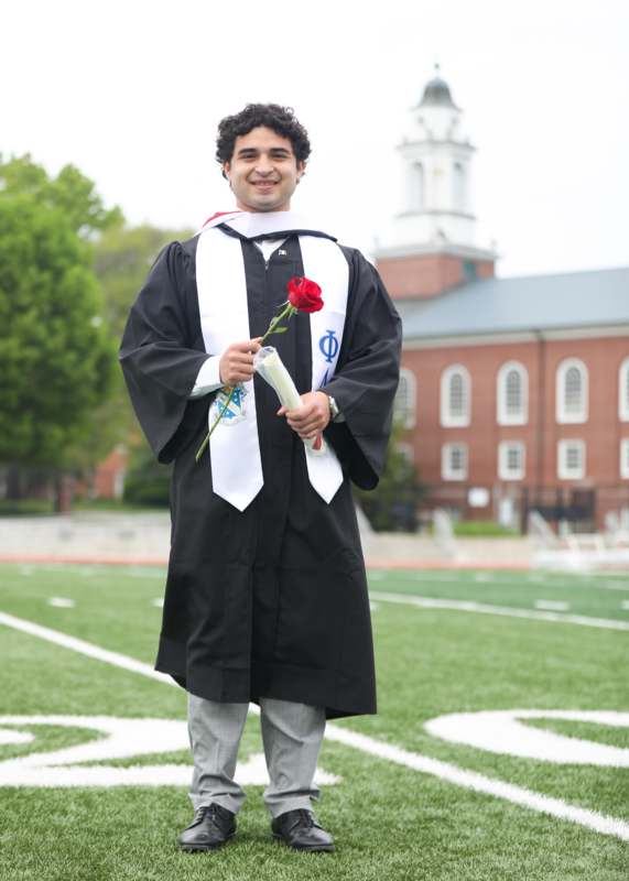 a man in a graduation gown holding a rose