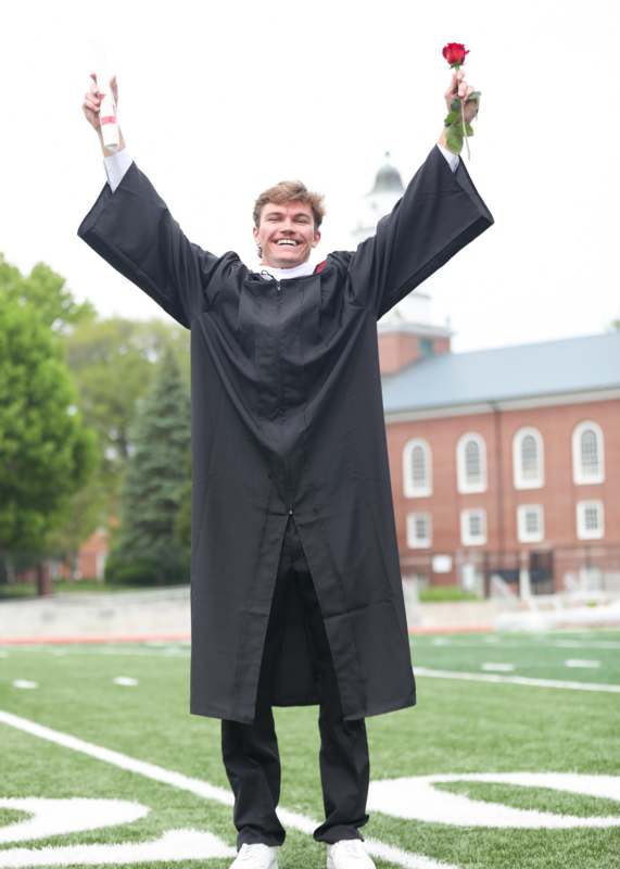 a man in a graduation gown holding up his hands